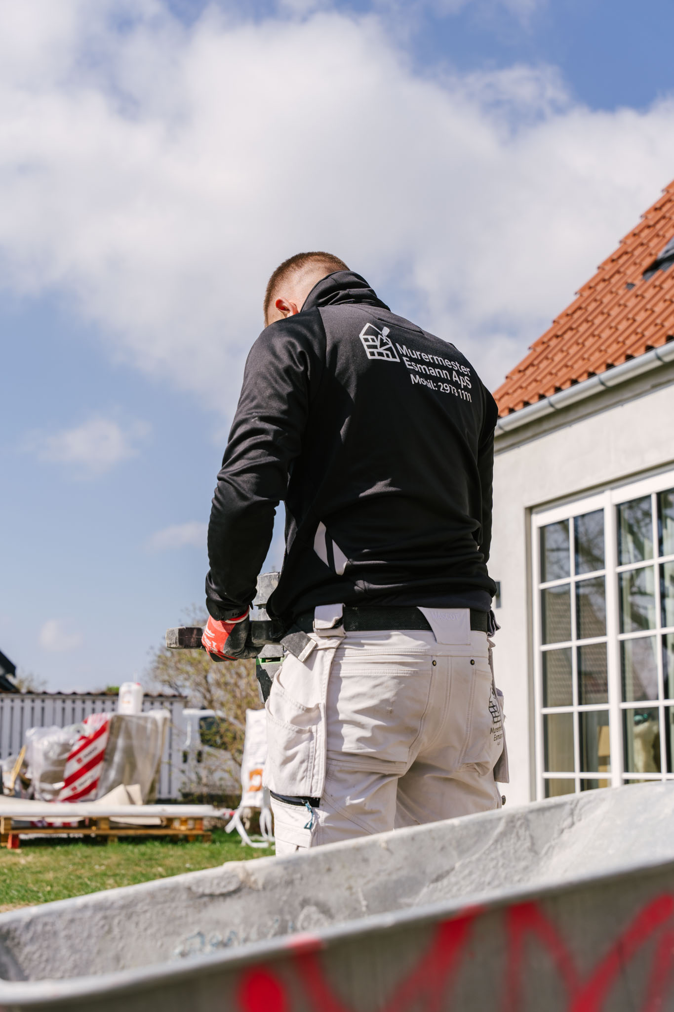 Pudsearbejde set bagfra — logo på arbejdsjakken